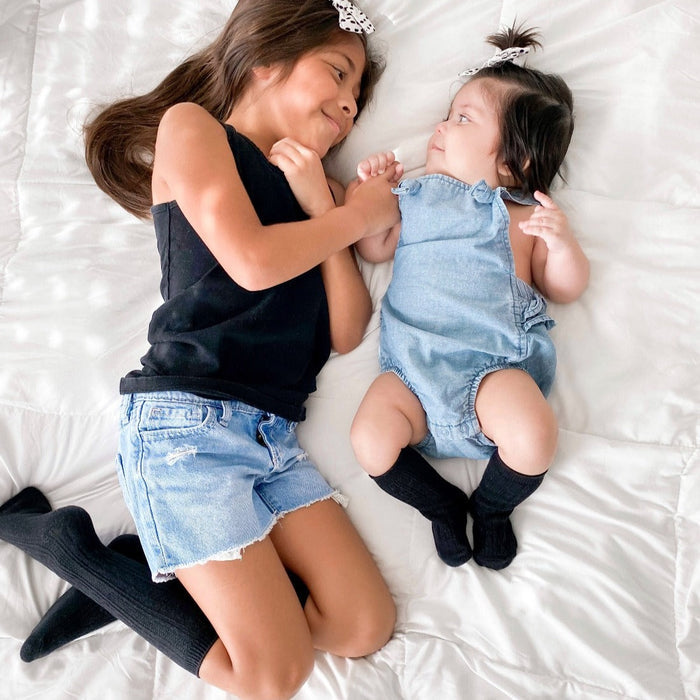sisters lounging together in matching black cable knit knee high socks