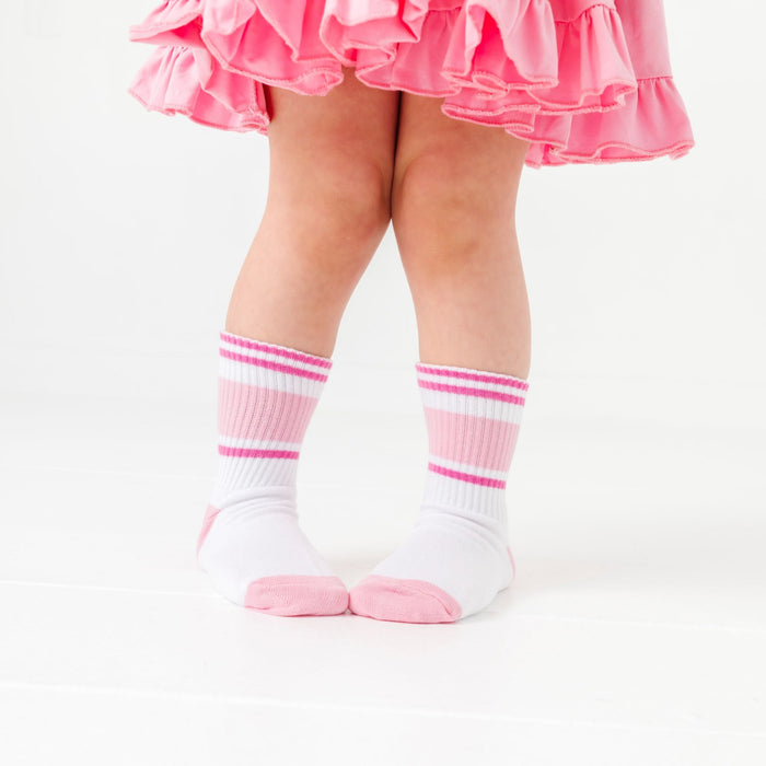 little girl in white crew socks with stripes in shades of pink and light pink toe and heel detail paired with pink twirl dress