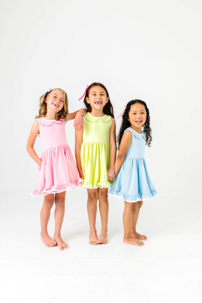 three girls in coordinating pink, lime-green and light blue twirl dresses with peter pan collars