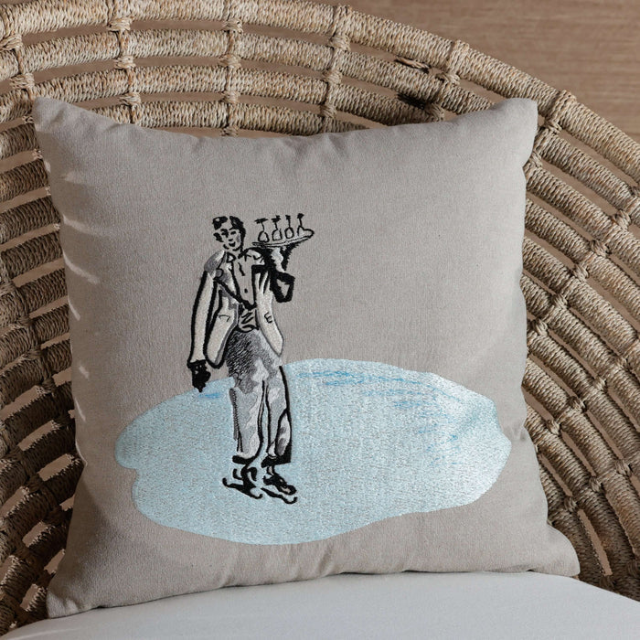Decorative pillow with a vintage-style illustration of a man in a suit on a wicker chair.