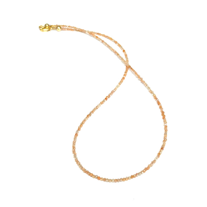 Sunstone necklace detail showing gold-filled clasp and warm peachy-gold round beads on a white background, front long view.