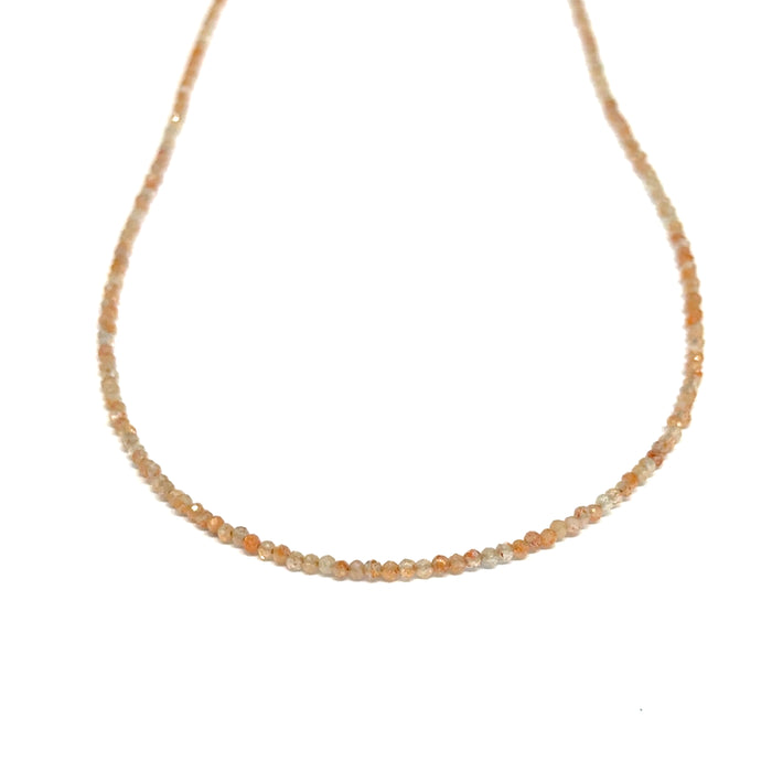 Sunstone necklace detail showing gold-filled clasp and warm peachy-gold round beads on a white background, front long hanging view.