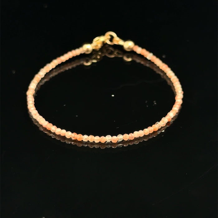 2mm faceted sunstone beaded  bracelet on a black background, front view.