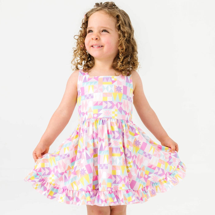 little girl posing in small world inspired geometric sleeveless twirl dress
