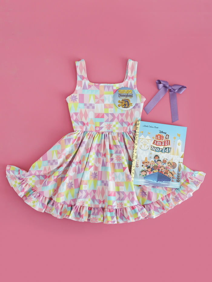 girl's small world inspired print twirl dress paired with purple satin hairbow, park button and book