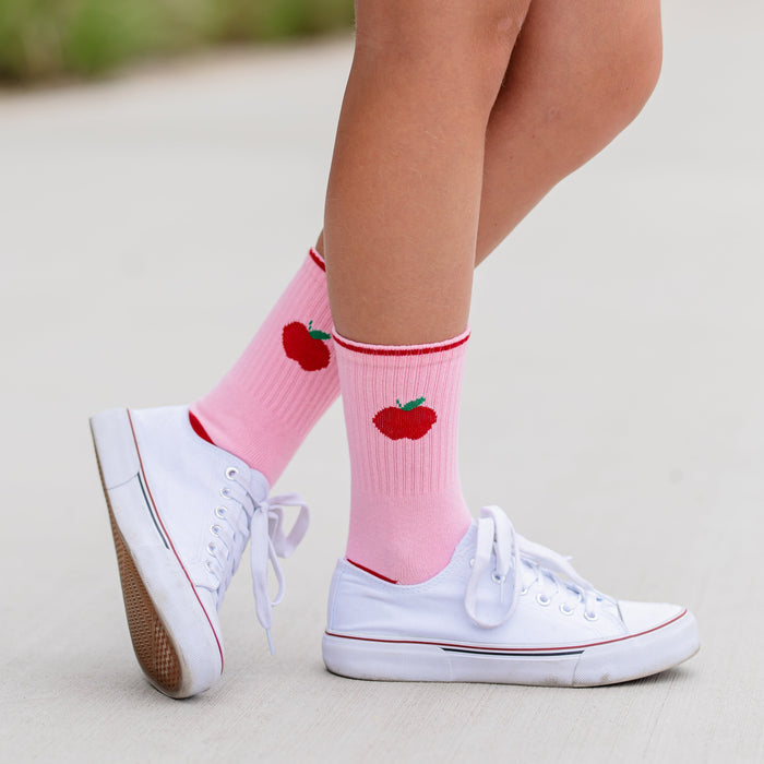girl in pink crew socks with red trim and red apple design at the ankle for back to school
