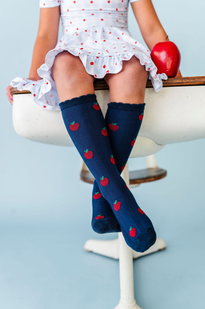 navy apple knee high socks on little girl sitting on desk