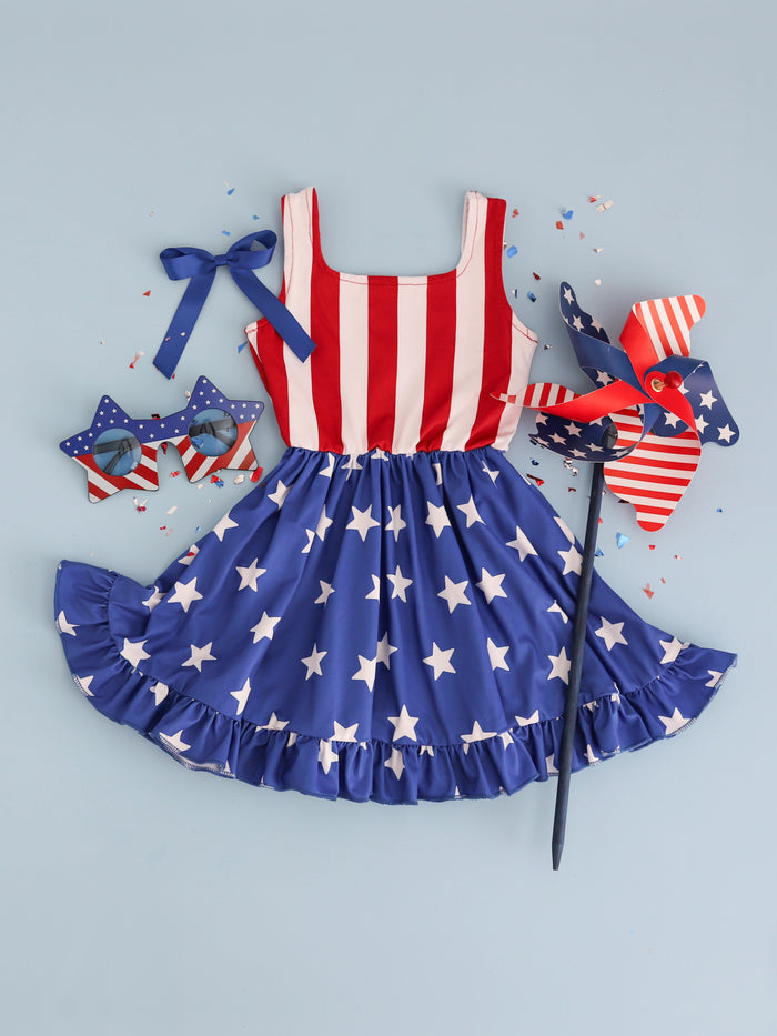 styled flat lay featuring American flag inspired sleeveless twirl dress paired with red, white and blue sunglasses, pinwheel and matching blue satin hair bow for the 4th