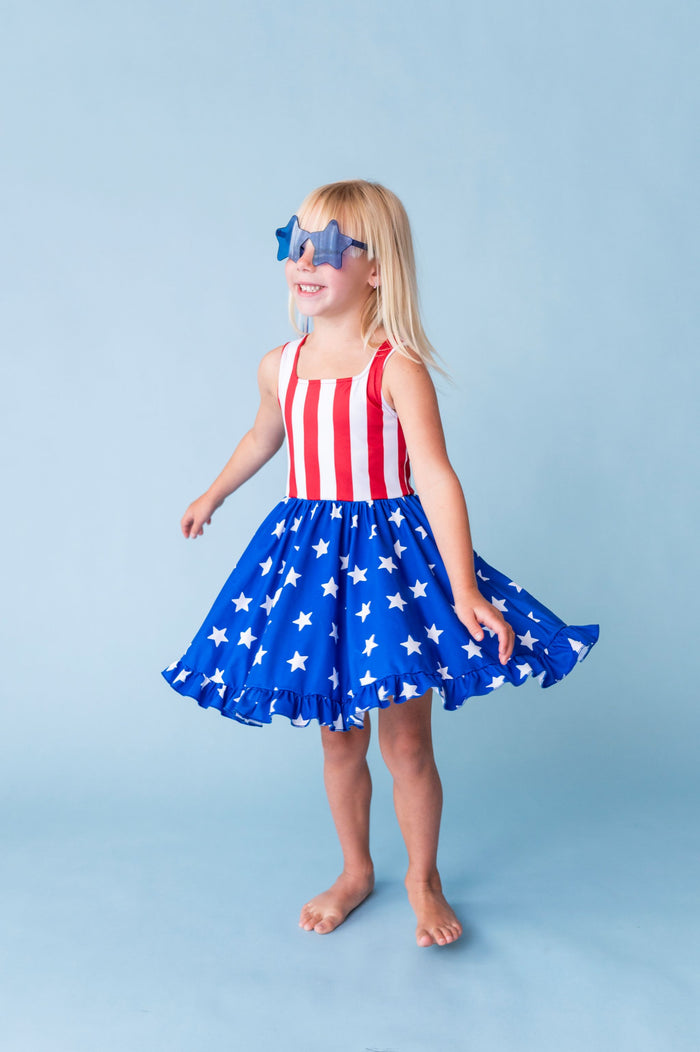 girl twirling in stars and stripes American flag inspired twirl dress and star sunnies for the 4th of July
