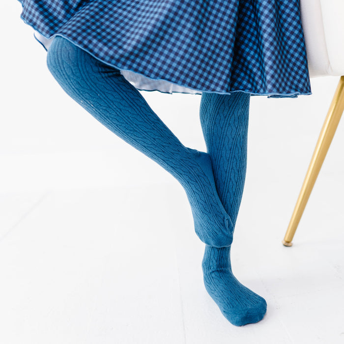 closeup of little girl in blue cable knit tights and matching gingham twirl dress for fall