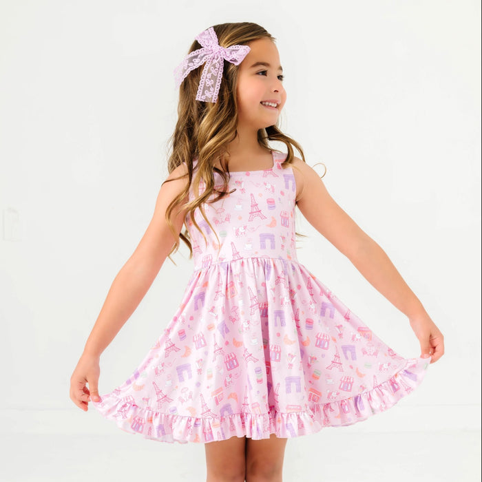 young girl posing in pink Paris themed sleeveless twirl dress featuring iconic Parisian landmarks and treats