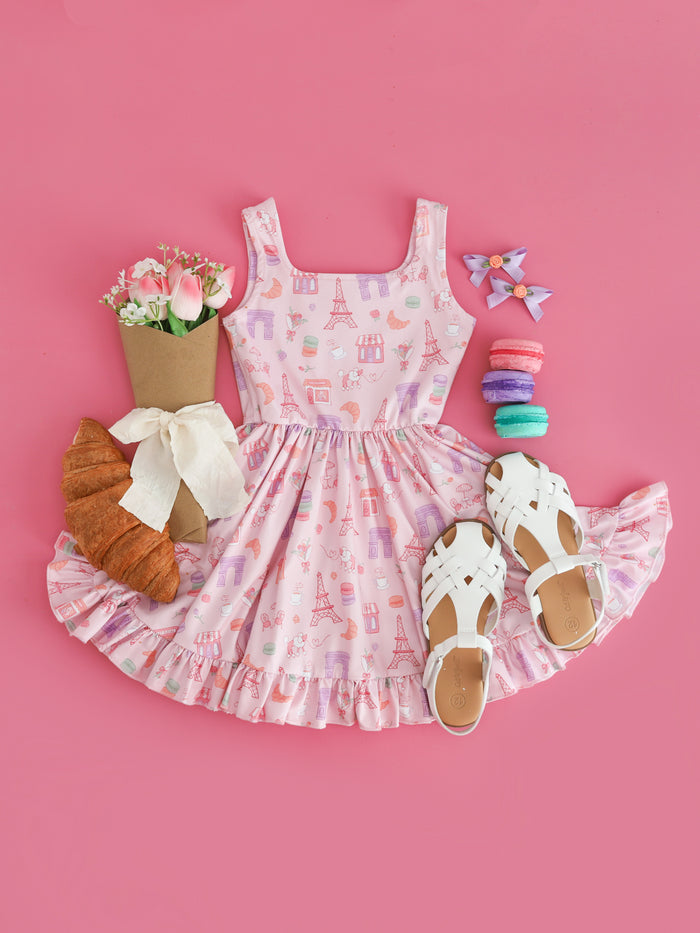 girls' Paris themed flat lay with Paris print tank twirl dress styled with croissants and macaroons and matching rosette pigtail bows