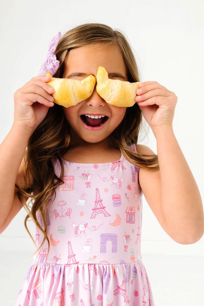 little girl holding croissants in pink paris themed twirl dress