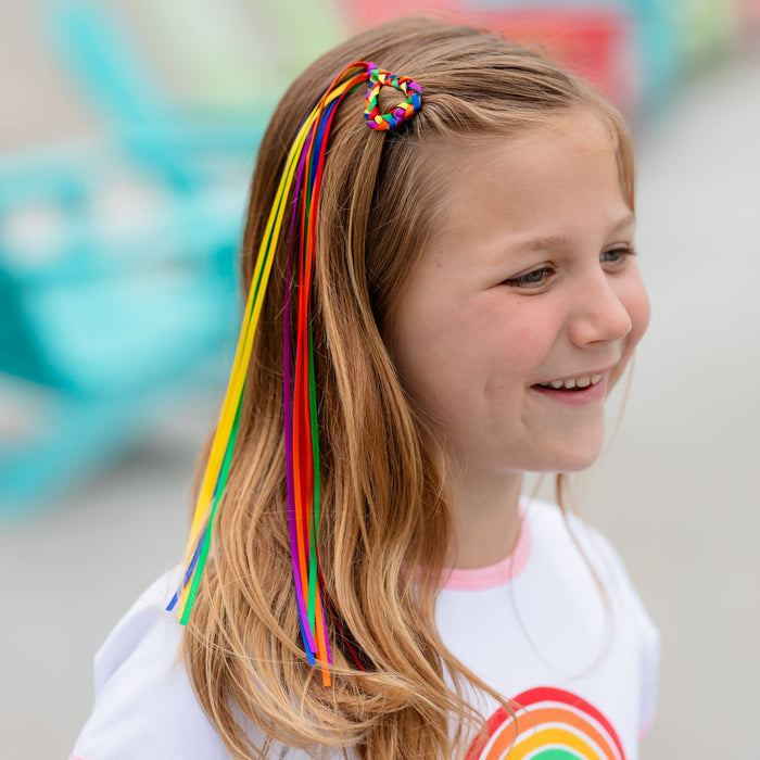 girl wearing rainbow braided heart shaped hair clip with ribbons for pride day