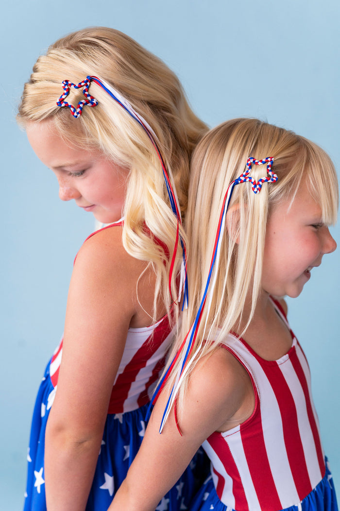 sisters in matching flag dresses paired with red, white and blue braided ribbon star clips