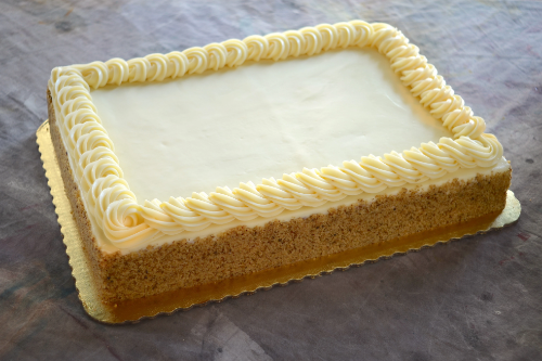 Large 9x13 sheet cake with white frosting, piped border, nut-coated sides, on a gold cardboard base.