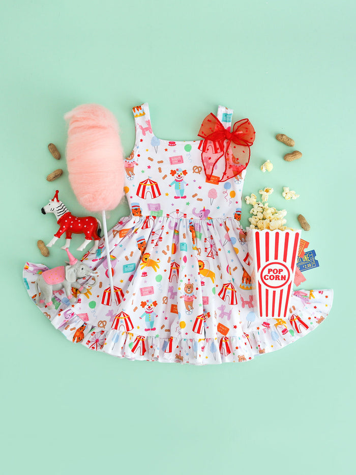 girls sleeveless twirl dress with circus characters, animals, treats and classic rides printed on white and paired with carnival treats