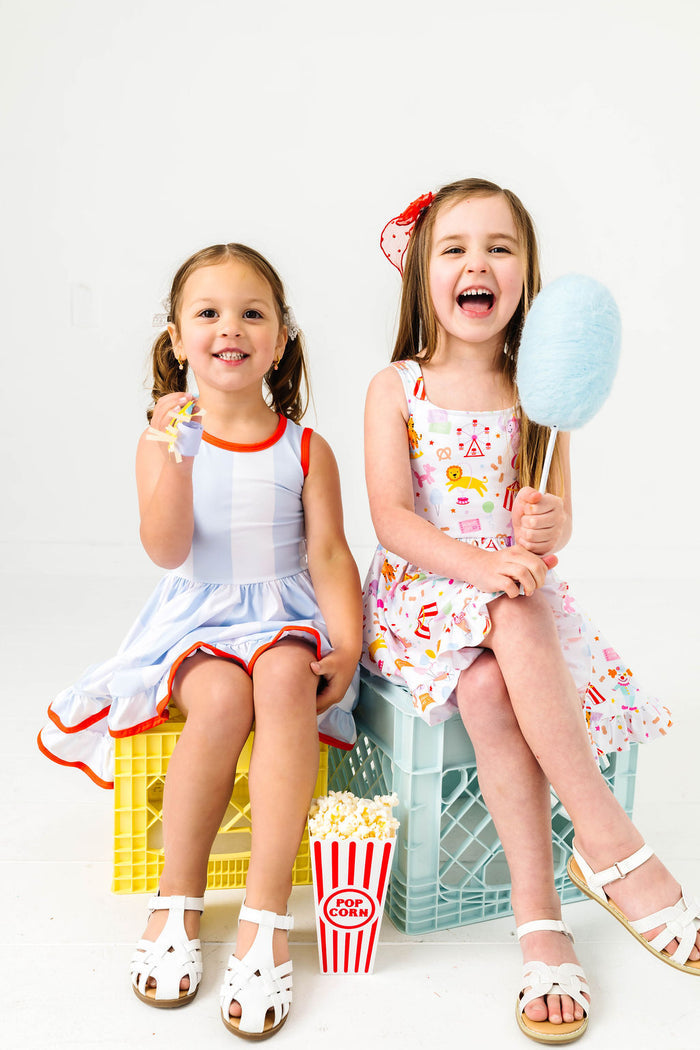 girls with cotton candy and popcorn wearing coordinating circus print and wide stripe twirl dresses