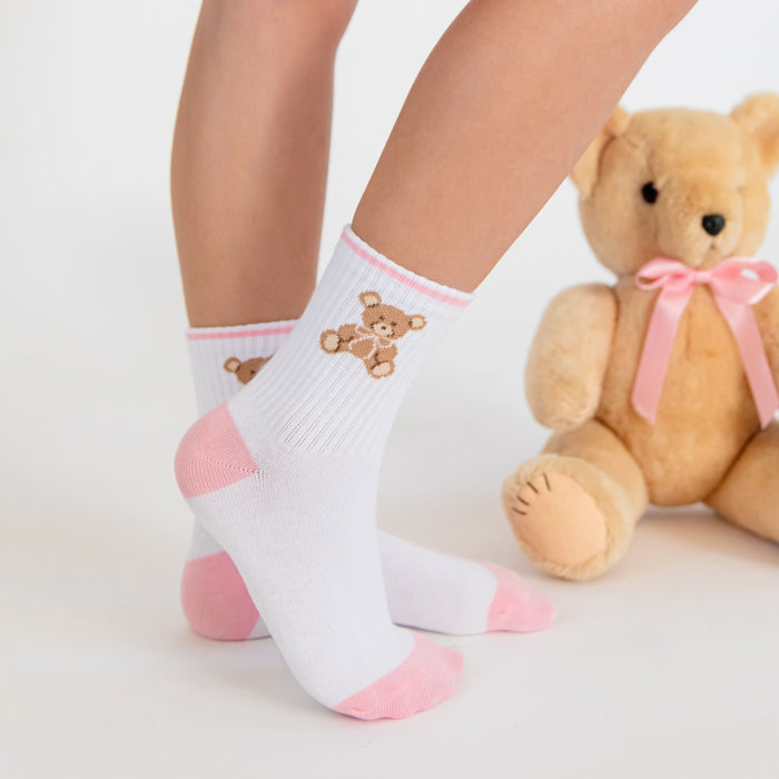 little girl standing by teddy bear with pink bow in matching crew socks with teddy design at the ankle