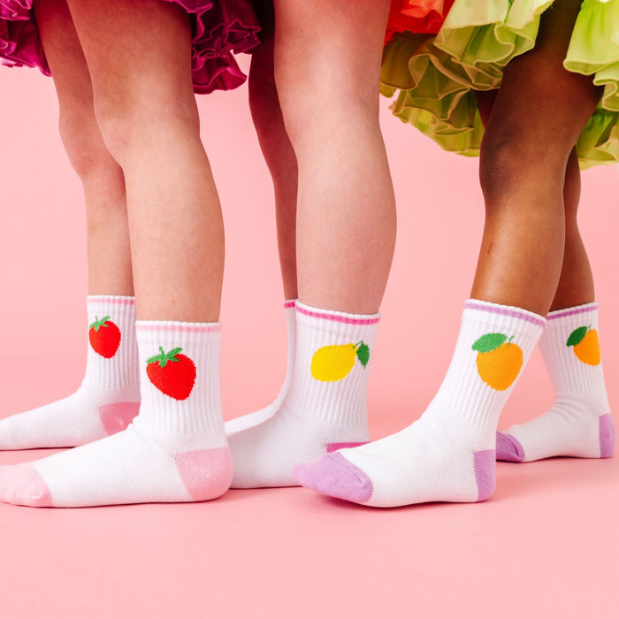 three girls in summer solid twirl dresses paired with white crew socks three pack with strawberry, lemon and orange designs