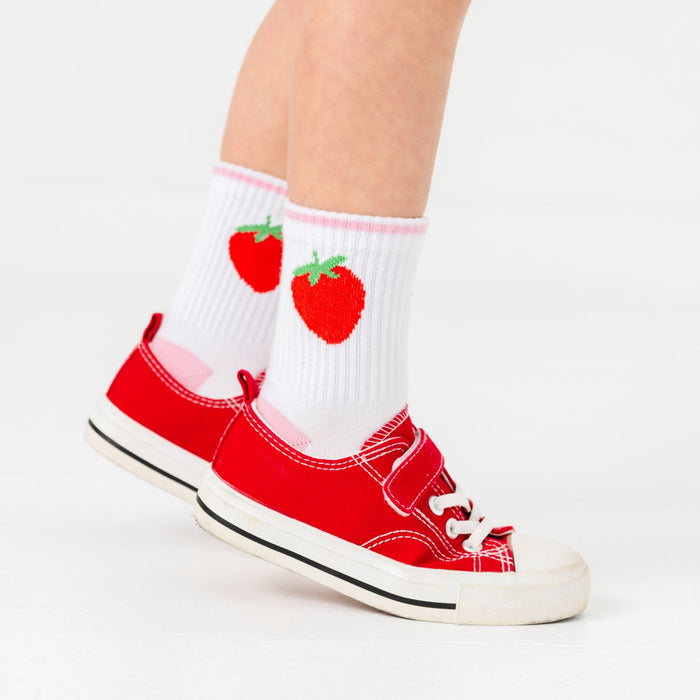 closeup of girl in white crew socks with red strawberry design and pink heel paired with red sneakers