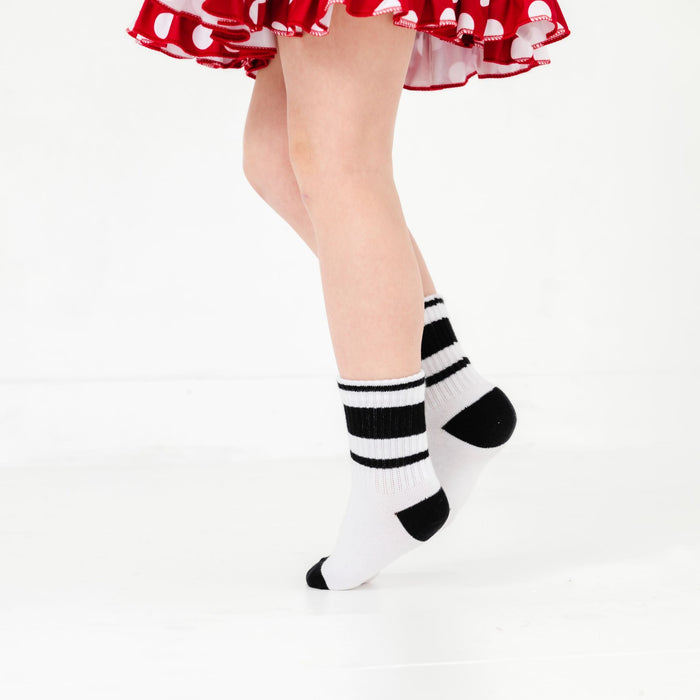 little girl in red Minnie dot dress paired with white crew socks with black heel, toe and stripes at ankle