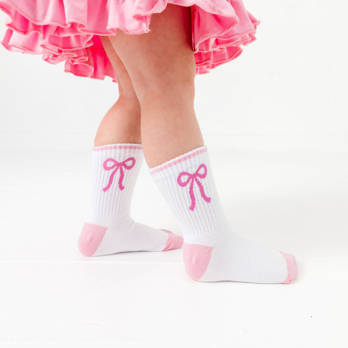 little girl in white crew socks with pink bow design and light pink toe and heel detail paired with pink twirl dress