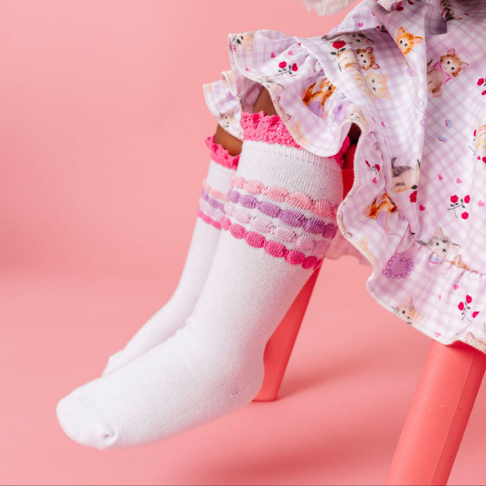 little girl sitting in vintage kitten print twirl dress and matching lace top knee high socks pastel pink and purple stripes