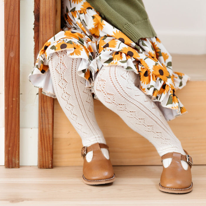 little girl in sunflower dress and matching ivory crochet knit tights