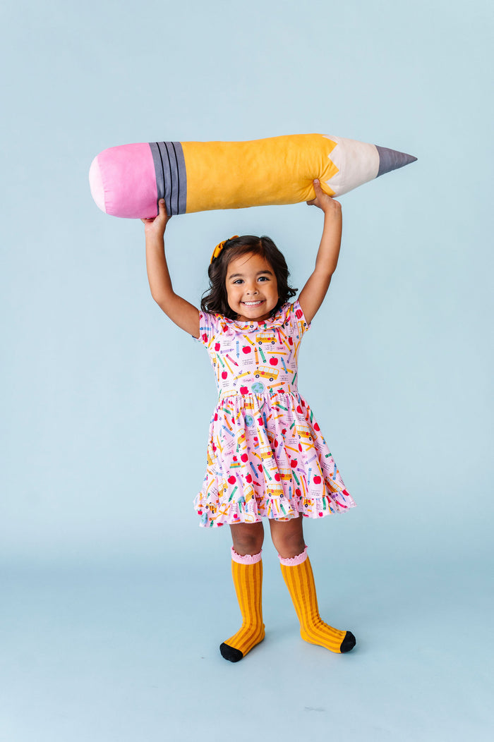 little girl wearing pink back to school themed dress with pencil knee high socks