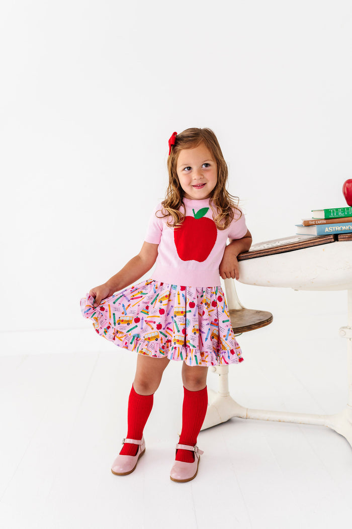 girl wearing pink first day of school themed outfit with red apple sweater tee and red knee high socks