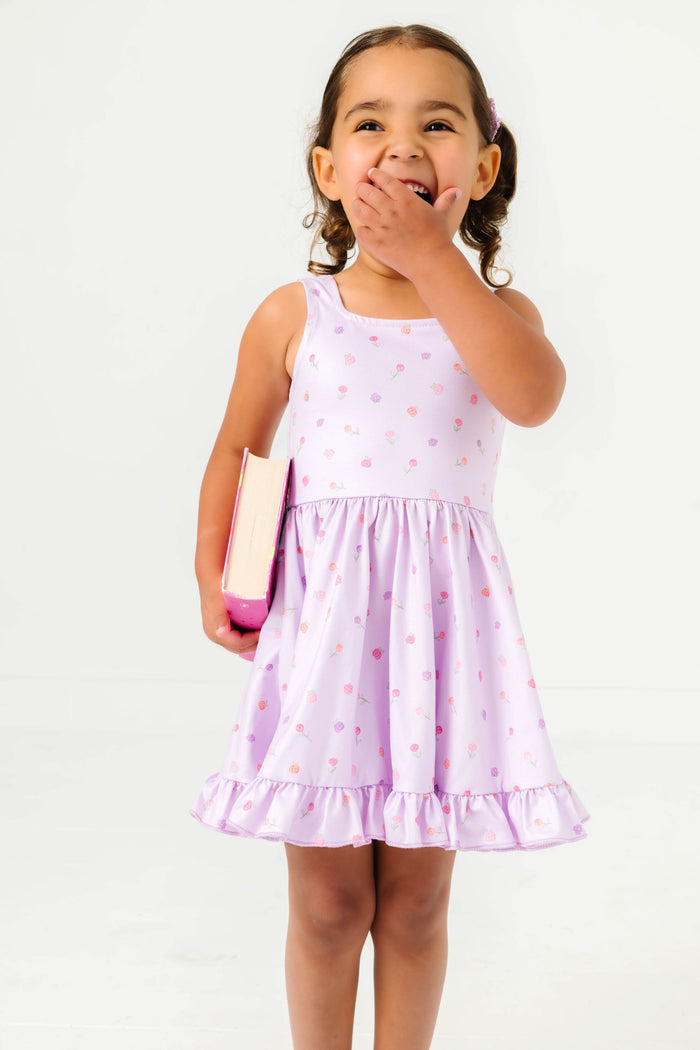 little girl holding book in light purple sleeveless twirl dress with tiny pastel rosette print