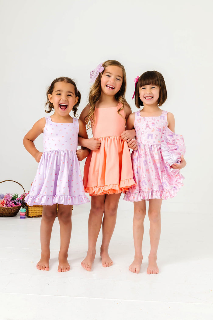 three girls in coordinating Paris themed dress print, floral print and peachy solid summer twirl dresses