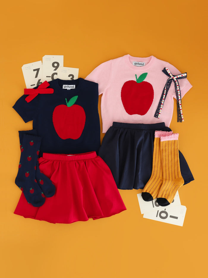 short sleeve red apple design sweaters in navy and pink paired with coordinating apple and pencil socks and bows