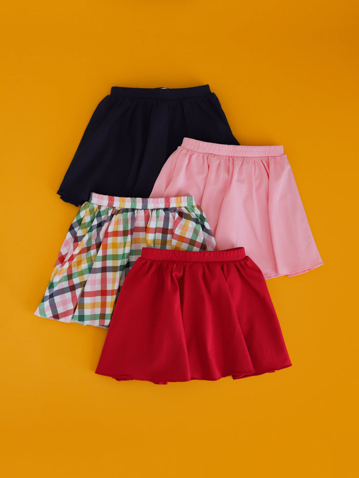 flat lay of skorts in navy, red, pink and rainbow gingham to match back to school collection