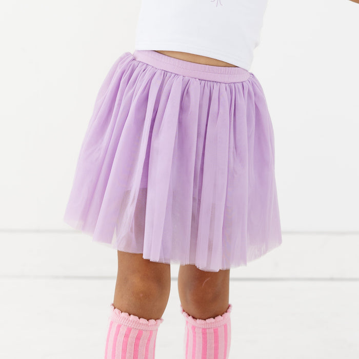 closeup of little girl in lavender tulle skirt with attached shorts and scallop trimmed pink striped knee high socks
