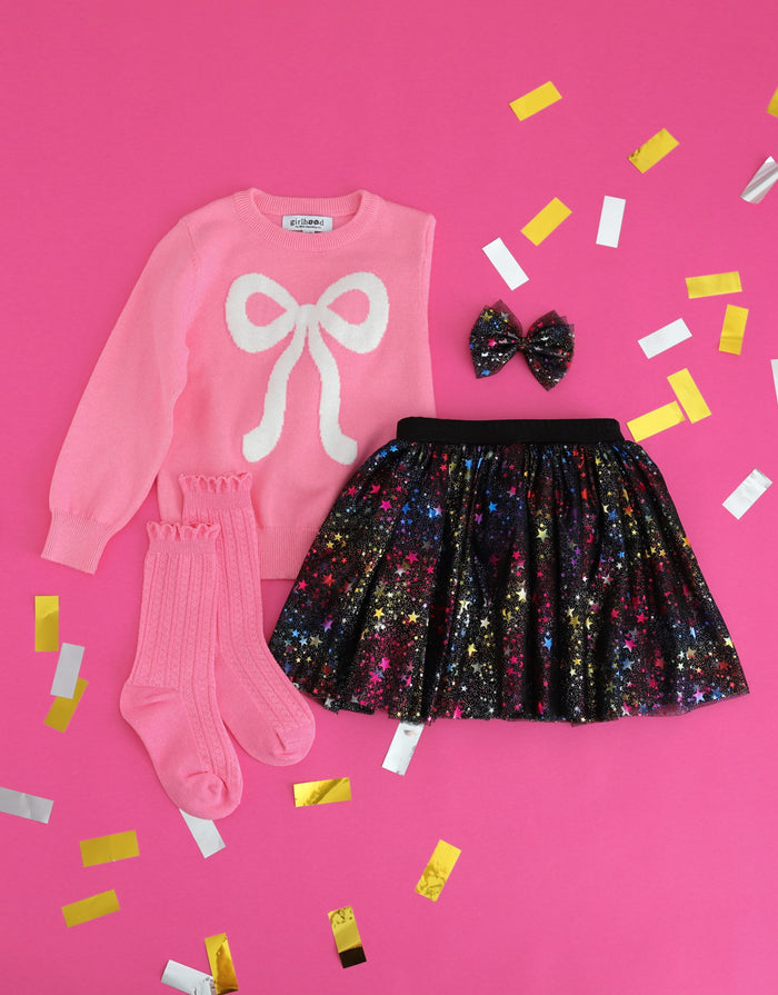 girls' pink cotton knit sweater with sparkly white bow design paired with black tutu skort with multi-color foil stars, matching tutu hair bow and pink knee socks for New Years