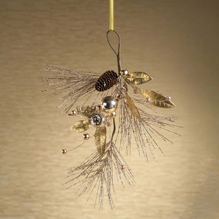 Decorative ornament with gold leaves, pinecones, and beads on a beige background