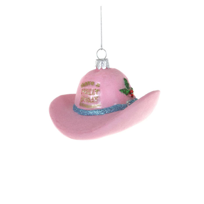 A pink felt cowboy hat Christmas ornament with gold glitter text reading 'have a holly dolly christmas, a blue glitter band, and a small holly accent, hanging against a white background.