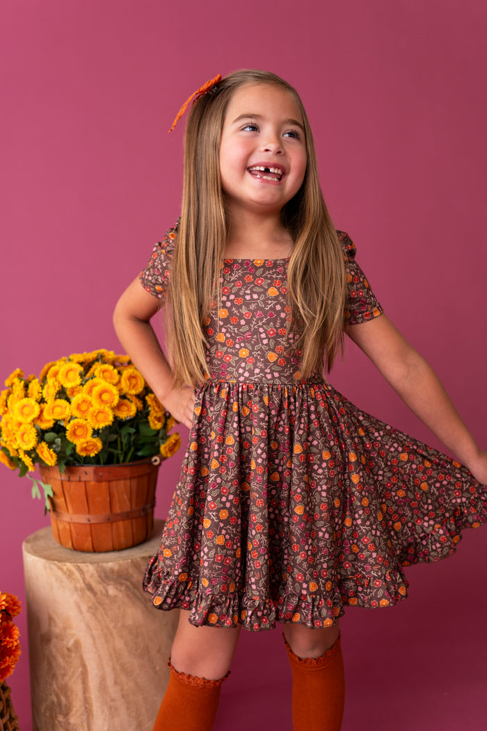 young girl in brown fall floral square neck twirl dress paired with knee socks and bow in pumpkin spice