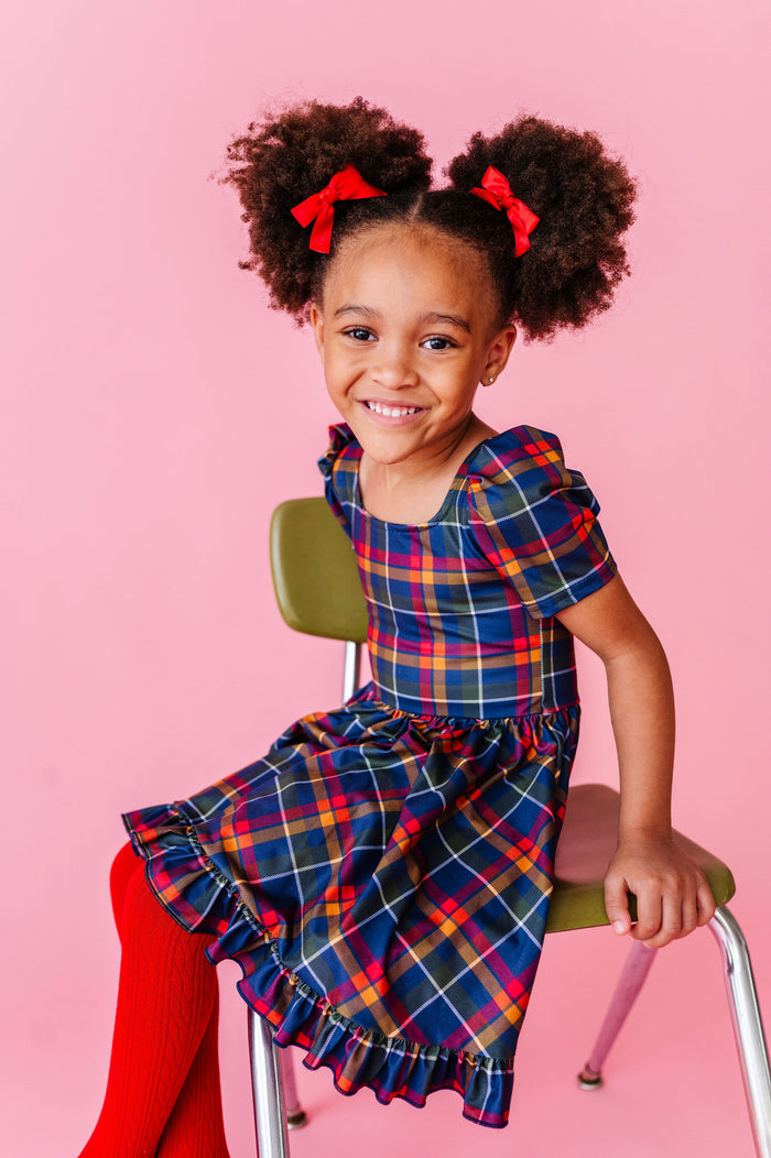 little girl wearing plaid dress with matching red tights and hair bows for back to school