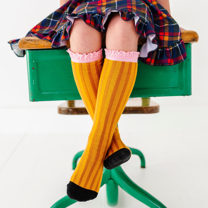 girl wearing pencil knee high socks with back to school plaid dress