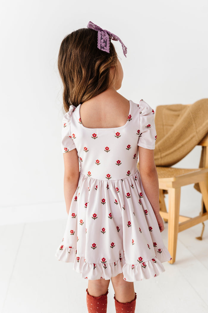 back view of square neck design on little girl's ivory with rust and amethyst flower print twirl dress