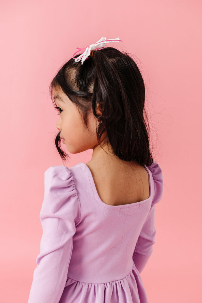 back view of little girl in square neck long sleeve lavender twirl dress
