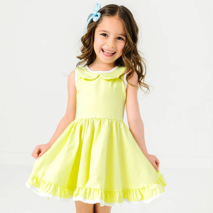 little girl in light yellow-green twirl dress with peter pan collar, white trim and light blue satin hair bow