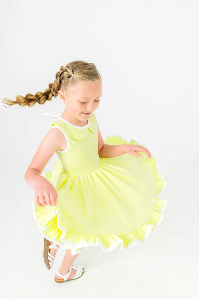 girl twirling in lime-green sleeveless summer twirl dress and white sandals
