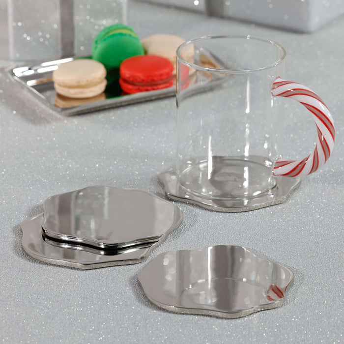 Clear glass mug with candy cane design handle on a reflective surface, with macarons in the background.