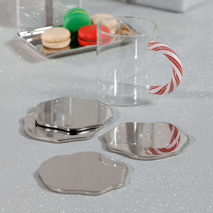 Clear mug with a candy cane handle on a reflective surface with silver coasters.