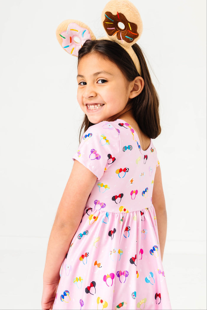 girl looking behind her in a pink twirl dress with magical princess ears on it and wearing fuzzy donut ears