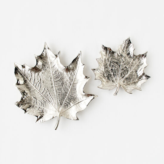 Two silver leaf-shaped dishes on a white background